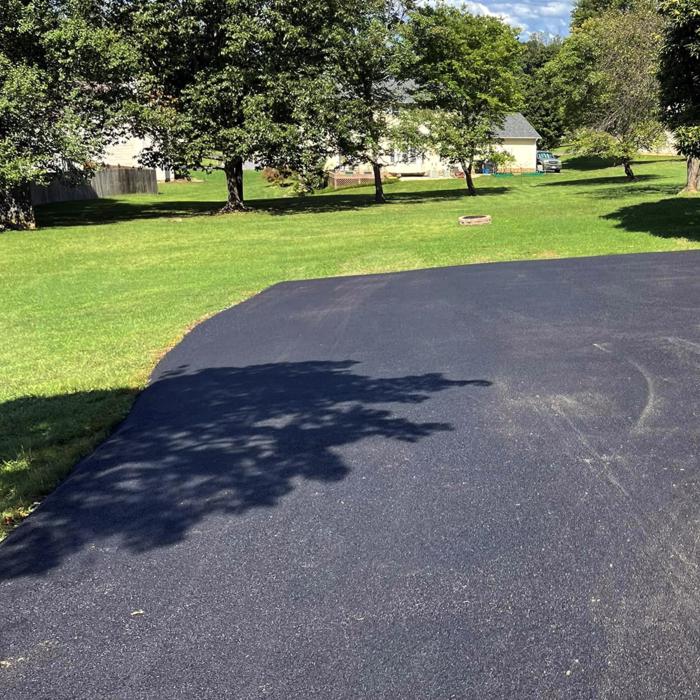 A newly paved asphalt driveway in front of a house